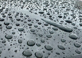 Big rain drops on the metal surface with sky reflection. After rain background