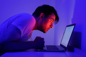 Focused Individual Experiencing Intense Concentration While Using Laptop in Dim Lighting