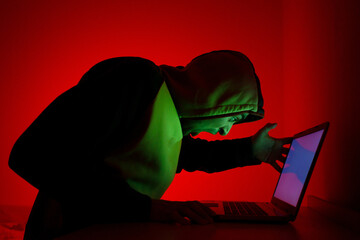 A Person in a Hooded Sweatshirt Engaged in Intense Computer Activity at Night