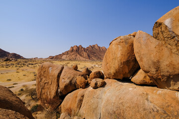 A stunning view of Spitzkoppe from the granite rocks of Damaraland, Namibia, under a clear blue sky.