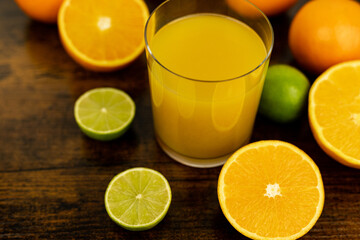 A healthy smoothie in glass with oranges and lime.Glass of orange juice, oranges