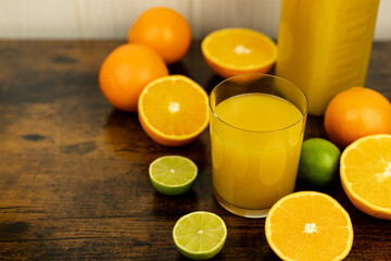 A healthy smoothie in glass with oranges and lime.Glass of orange juice, oranges