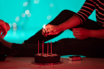 Woman lighting candles on birthday cake in atmospheric setting