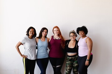 Group of diverse women in workout attire, smiling and standing together. Fitness and diversity are highlighted in this image of women in activewear. Diverse athletic women at gym.