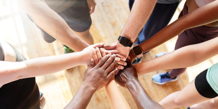 Diverse group of men and women, putting hands together in a circle. Teamwork, unity, and collaboration emphasized. Hands in unity, showing teamwork and collaboration. Team stacking hands together.