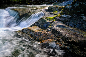 Water cascades softly over rocks, creating a peaceful atmosphere in this scenic riverscape...