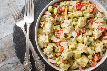 Creamy Pesto Chicken Salad with celery, onion, bell pepper and almond flakes close up on the table. Horizontal top view from above