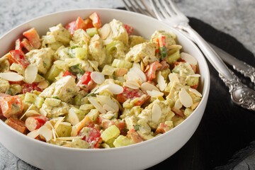 Creamy Pesto Chicken Salad with celery, onion, bell pepper and almond flakes close up on the table. Horizontal