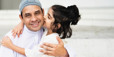 A child kisses an adult wearing a traditional cap, both smiling warmly. The scene captures a moment...