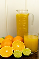 Cut oranges and limes on the table. A glass of citrus juice.Freshly orange juice