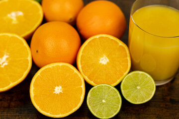 Cut oranges and limes on the table. A glass of citrus juice.Freshly orange juice