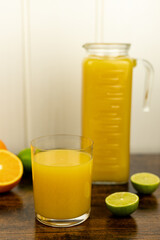 Cut oranges and limes on the table. A glass of citrus juice.Freshly orange juice