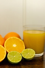 Cut oranges and limes on the table. A glass of citrus juice.Freshly orange juice