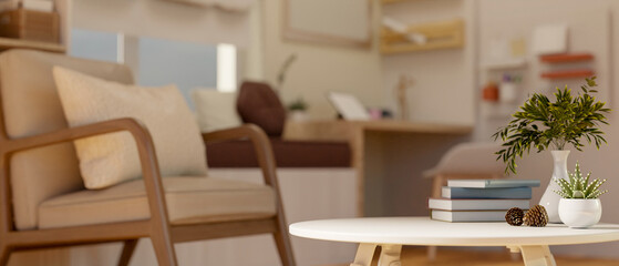 The wooden armchair beside the round table with books and decors in the cosy bedroom or living room.