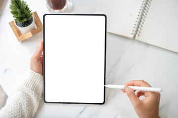 The left hand holding blank screen tablet with stylus pencil pointing at the screen in right hand.