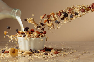 Muesli and milk in motion on a beige background.