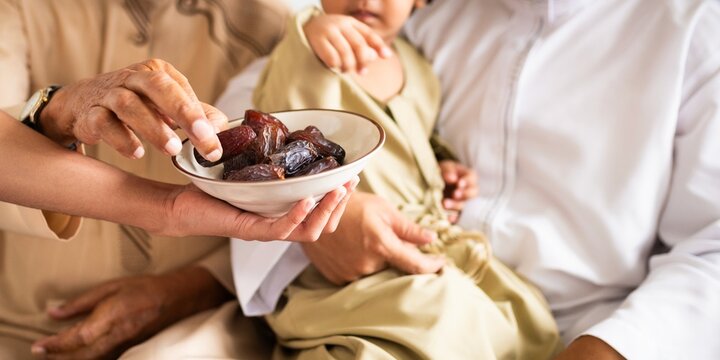 Close-up of hands sharing dates, symbolizing hospitality and tradition. A muslim family gathering, sharing dates, and cultural tradition in focus. Muslim family eating dates at end of Ramadan feast.
