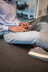 Obraz premium Unrecognizable man studying or working on laptop sitting on floor
