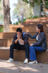 University student comforting sad classmate sitting on campus stairs