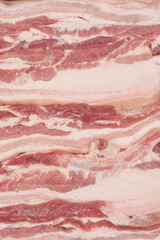 A close-up, top-down view of thick cuts of raw pork belly, showcasing the distinct layers of fat and meat