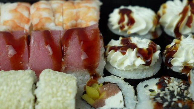 Set of sushi rolls close-up. Rolls with rice, tiger shrimp, salmon, tuna, eel. Appetizing delicious fresh Japanese food. Seafood. Advertisement for sushi rolls. Top view. High quality 4k footage