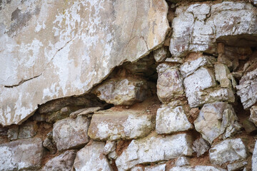 
a masonry wall made of stones of various sizes with an uneven surface and color.