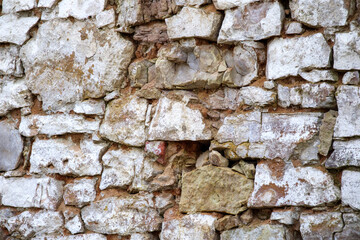 
a masonry wall made of stones of various sizes with an uneven surface and color.