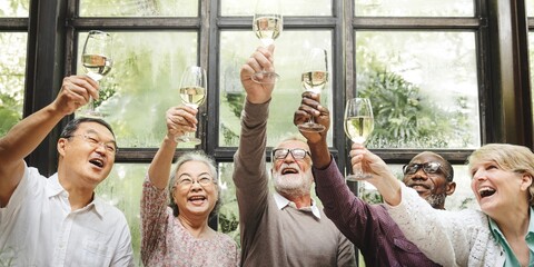 Group of diverse seniors raising glasses in celebration. Elderly friends, men and women, enjoying a...