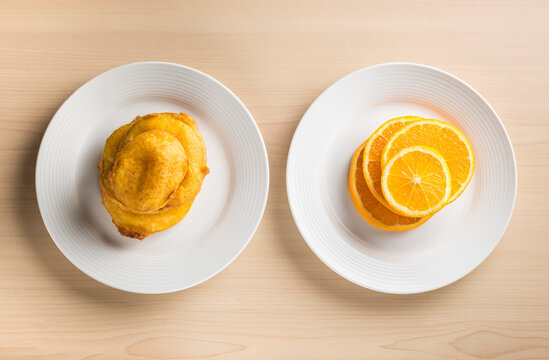 Junk food vs healthy food. An idea illustrated with fried food and fresh fruits placed side by side. Slices of fresh orange fruit placed along with deep fried potato bhajiya. 