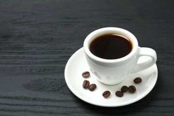 Cup of coffee with fresh coffee beans on wooden background