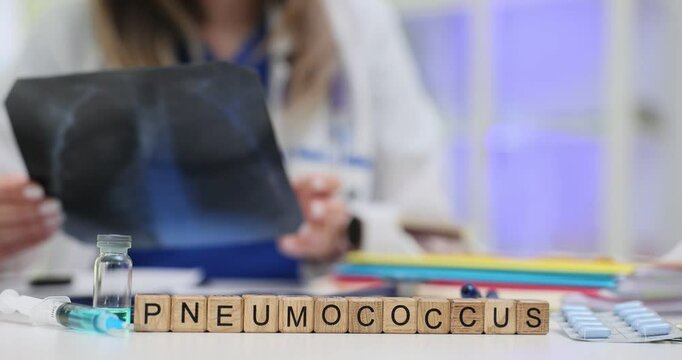 A doctor carefully evaluates an Xray to diagnose pneumonia while Scrabble tiles spell out the word Pneumococcus