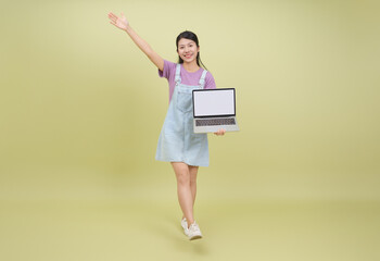 Fototapeta premium Young woman with laptop smiling and waving, wearing casual outfit in a light studio setting during daytime