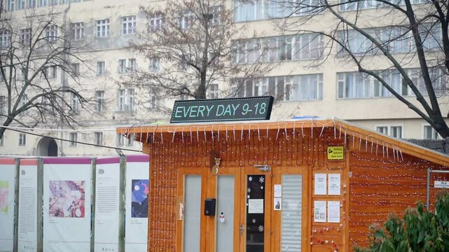 Small wooden COVID test booth with a digital sign and festive lights outside