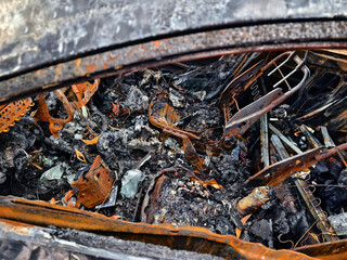 Charred remnants of a vehicle interior left behind after a devastating fire incident