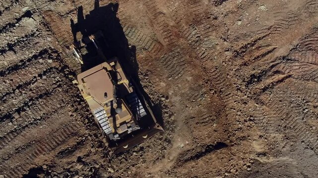 Top down view of heavy duty bulldozer pushing rocky soil, levelling