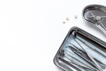 Dental crowns with steel instruments for dental prosthetics, top view. Dentist desk, white...