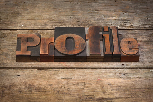 profile, word written with vintage letterpress printing blocks on rustic wooden background, angled view