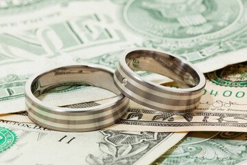 Pair of engagement or wedding rings on dollar bills
