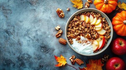 Fototapeta premium Homemade granola breakfast bowl with yogurt, caramelized apples, pumpkin, nuts, and cinnamon, arranged on a textured stone background.