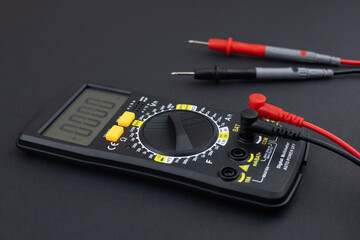 Digital multimeter with probes and display on dark background.