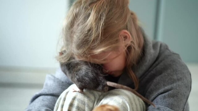 Teenage girl holding pet rat in hands at home. Cute teenager having fun playing with rat. Children and pets lifestyle concept.
