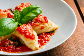 Culurgionis ogliastrini conditi con sugo e ripieni di pecorino, patate e menta, cibo tradizionale sardo, cucina italiana 