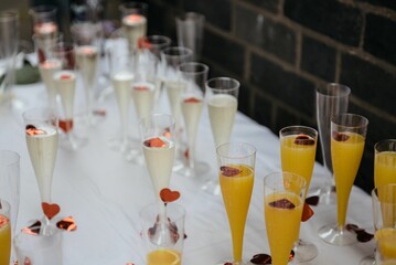 Table is set with glasses of champagne and orange juice, some with fruit, ready for a celebration.