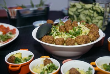 Buffet table features bowls of meatballs and pasta, alongside other dishes, ready for guests.