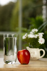 An apple and a glass of water on the table. Treatment of vitamin deficiency