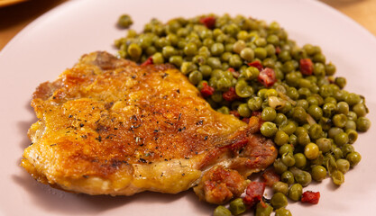 Delicious crispy chicken with peas as a side dish on a plate