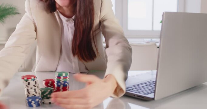 Faceless businesswoman happy about victory in online casino, sitting in front of laptop and clenching fists as sign of success, gabbing pocker chips, plays in roulette, being addicted 
