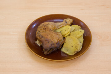 A plate of chicken and potatoes on a wooden table