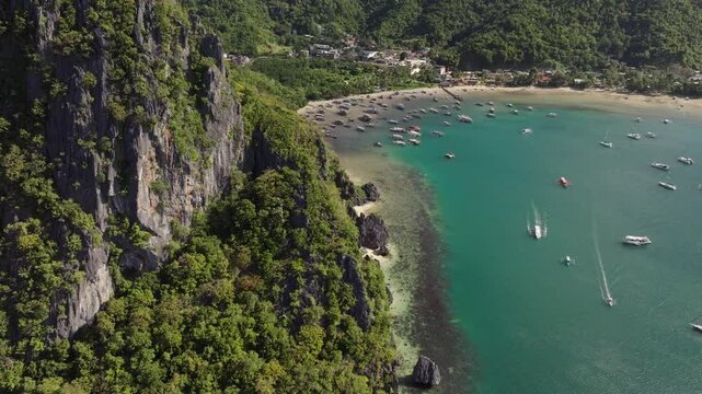 Drone flight over Corong Corong Beach with boats along the shore, offering a scenic view of the beach and Las Cabanas in the distance.
