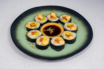 A plate of sushi with a green plate and a black plate